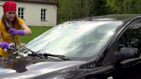 Jeune femme dans la chemise jaune et l'automobile de lavage de foulard rouge dans la cour banque de vidéos Jeune femme dans la chemise jaune et l'automobile de lavage de foulard rouge dans la cour banque de vidéos