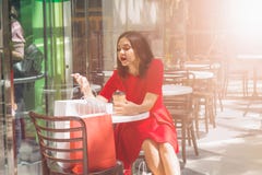 jeune femme de brune dans la robe rouge regardant dans des sacs à provisions dans un café après l'achat le mail image stock jeune femme de brune dans la robe rouge regardant dans des sacs à provisions dans un café après l'achat le mail image stock