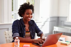 Jeune femme de couleur à l'aide de l'ordinateur portable à un bureau, plan rapproché image stock Jeune femme de couleur à l'aide de l'ordinateur portable à un bureau, plan rapproché image stock