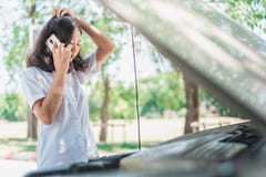 Jeune femme de l'Asie s'asseyant devant sa voiture, essai ? la r?clamation l'aide avec sa voiture d?compos? photos libres de droits Jeune femme de l'Asie s'asseyant devant sa voiture, essai ? la r?clamation l'aide avec sa voiture d?compos? photos libres de droits