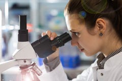 Jeune femme de scientifique à l'aide d'un microscope dans une science images libres de droits Jeune femme de scientifique à l'aide d'un microscope dans une science images libres de droits