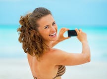 Jeune femme de sourire prenant la photo sur la plage images libres de droits Jeune femme de sourire prenant la photo sur la plage images libres de droits