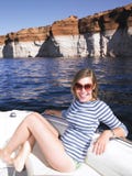 Jeune femme de sourire s'asseyant dans le bateau photos libres de droits Jeune femme de sourire s'asseyant dans le bateau photos libres de droits