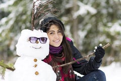 Jeune femme de sourire étreignant le bonhomme de neige photo stock Jeune femme de sourire étreignant le bonhomme de neige photo stock
