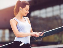 Jeune femme faisant une pause de l'exercice dehors avec le téléphone portable photo libre de droits Jeune femme faisant une pause de l'exercice dehors avec le téléphone portable photo libre de droits