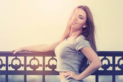Jeune femme heureuse de mode dans le dessus gris de culture et costume de jupe se penchant sur la balustrade photo stock Jeune femme heureuse de mode dans le dessus gris de culture et costume de jupe se penchant sur la balustrade photo stock