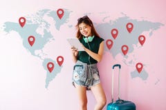 Jeune femme heureuse de voyageur se tenant avec la valise et employant Tabl photographie stock Jeune femme heureuse de voyageur se tenant avec la valise et employant Tabl photographie stock
