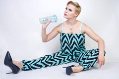 Jeune femme plus de charme de taille dans la salopette bleue noire avec le verre de l'eau sur le fond blanc dans le studio joli w images stock Jeune femme plus de charme de taille dans la salopette bleue noire avec le verre de l'eau sur le fond blanc dans le studio joli w images stock