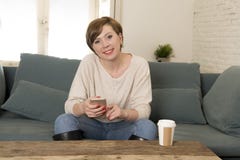 Jeune femme rouge attirante et heureuse de cheveux reposant à la maison le sofa c images libres de droits Jeune femme rouge attirante et heureuse de cheveux reposant à la maison le sofa c images libres de droits