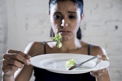 Jeune femme tenant le plat avec de la laitue ridicule en tant que son symbole de nourriture du trouble nutritif de régime fou photos libres de droits Jeune femme tenant le plat avec de la laitue ridicule en tant que son symbole de nourriture du trouble nutritif de régime fou photos libres de droits