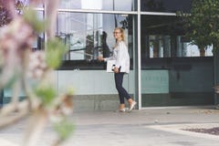 Jeune femme tenant un ordinateur portable blanc et entrant dans un bâtiment image stock Jeune femme tenant un ordinateur portable blanc et entrant dans un bâtiment image stock