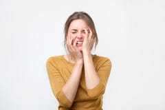Jeune femme épuisée dans le chandail jaune touchant sa tête avec des yeux fermés photo stock Jeune femme épuisée dans le chandail jaune touchant sa tête avec des yeux fermés photo stock
