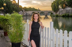 Jeune fille avec du charme dans une robe pendant une promenade au coucher du soleil le long du remblai de rivière du Tibre près d image stock Jeune fille avec du charme dans une robe pendant une promenade au coucher du soleil le long du remblai de rivière du Tibre près d image stock