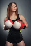 Jeune fille de forme physique avec les gants bloxing regardant la caméra au-dessus de l'art noir de fond image libre de droits Jeune fille de forme physique avec les gants bloxing regardant la caméra au-dessus de l'art noir de fond image libre de droits
