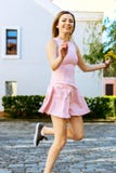 Jeune fille heureuse sautant dans une robe rose avec un bouquet images stock Jeune fille heureuse sautant dans une robe rose avec un bouquet images stock