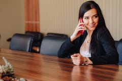 Jeune fille ?motive attirante dans des v?tements de style d'affaires se reposant au bureau avec le t?l?phone dans le bureau ou l' photo libre de droits Jeune fille ?motive attirante dans des v?tements de style d'affaires se reposant au bureau avec le t?l?phone dans le bureau ou l' photo libre de droits
