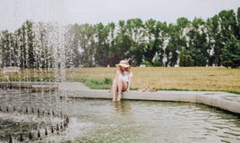 Jeune fille mouillant sa fontaine de piscine de pieds image stock Jeune fille mouillant sa fontaine de piscine de pieds image stock
