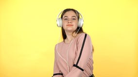 Jeune fille écoutant la musique dans de grands écouteurs blancs banque de vidéos Jeune fille écoutant la musique dans de grands écouteurs blancs banque de vidéos