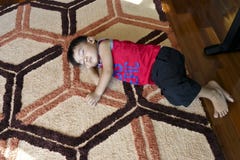 Jeune garçon endormi sur un tapis coloré sur le plancher images stock Jeune garçon endormi sur un tapis coloré sur le plancher images stock