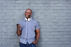 Jeune homme africain heureux avec les écouteurs et le téléphone portable Photo libre de droits Jeune homme africain heureux avec les écouteurs et le téléphone portable Photo libre de droits