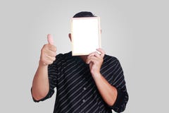 Jeune homme asiatique couvrant son visage de petit tableau blanc image libre de droits Jeune homme asiatique couvrant son visage de petit tableau blanc image libre de droits
