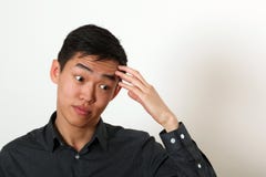Jeune homme asiatique réfléchi touchant son front photos stock Jeune homme asiatique réfléchi touchant son front photos stock