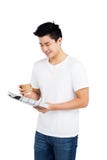 Jeune homme ayant le café et lisant le journal Photos libres de droits Jeune homme ayant le café et lisant le journal Photos libres de droits