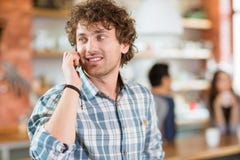Jeune homme bouclé moderne heureux attirant parlant au téléphone portable photos stock Jeune homme bouclé moderne heureux attirant parlant au téléphone portable photos stock