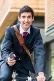 Jeune homme d'affaires multitâche montant une bicyclette pour travailler photo stock Jeune homme d'affaires multitâche montant une bicyclette pour travailler photo stock