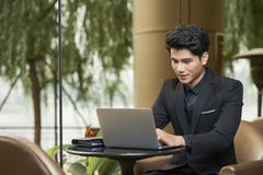 Jeune homme d'affaires travaillant sur l'ordinateur portatif image libre de droits Jeune homme d'affaires travaillant sur l'ordinateur portatif image libre de droits