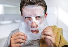 Jeune homme effray? et ?tonn? ? la maison utilisant le masque facial de papier de beaut? nettoyant faisant le traitement facial a photos stock Jeune homme effray? et ?tonn? ? la maison utilisant le masque facial de papier de beaut? nettoyant faisant le traitement facial a photos stock