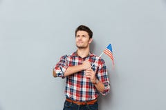 Jeune homme fier patriote tenant et tenant le drapeau des Etats-Unis Image libre de droits Jeune homme fier patriote tenant et tenant le drapeau des Etats-Unis Image libre de droits