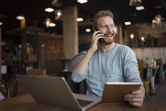Jeune homme heureux ayant l'appel téléphonique en café photographie stock Jeune homme heureux ayant l'appel téléphonique en café photographie stock