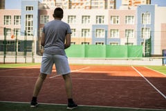 Jeune homme jouant le tennis dans la cour d'arrière cour d'école photo libre de droits Jeune homme jouant le tennis dans la cour d'arrière cour d'école photo libre de droits