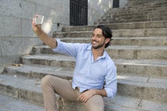 Jeune homme latin attirant sur l'escalier de ville prenant la photo de selfie ayant l'amusement au téléphone portable photographie stock libre de droits Jeune homme latin attirant sur l'escalier de ville prenant la photo de selfie ayant l'amusement au téléphone portable photographie stock libre de droits