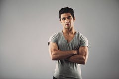 Jeune homme musculaire posant sur le fond gris image stock Jeune homme musculaire posant sur le fond gris image stock