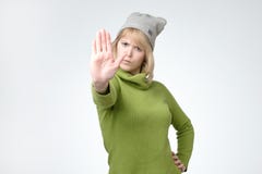 Jeune jolie fille sérieuse dans le signe vert d'arrêt d'apparence de chandail et de chapeau photos libres de droits Jeune jolie fille sérieuse dans le signe vert d'arrêt d'apparence de chandail et de chapeau photos libres de droits