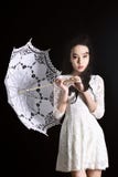 Jeune modèle mince dans la robe légère d'été avec un parapluie en filigrane posant dans le studio Fond noir image libre de droits Jeune modèle mince dans la robe légère d'été avec un parapluie en filigrane posant dans le studio Fond noir image libre de droits