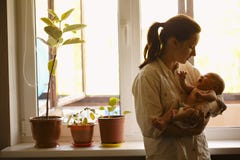 Jeune mère avec le bébé à la maison photographie stock Jeune mère avec le bébé à la maison photographie stock