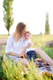 Jeune mère blonde embrassant peu d'enfant sur le plaid, herbe sur le fond image libre de droits Jeune mère blonde embrassant peu d'enfant sur le plaid, herbe sur le fond image libre de droits