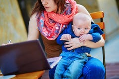 Jeune mère de fonctionnement avec son fils dans un café photos stock Jeune mère de fonctionnement avec son fils dans un café photos stock