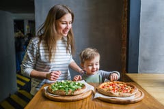 Jeune mère et petit fils mignon manger de la pizza dans le restaurant photographie stock Jeune mère et petit fils mignon manger de la pizza dans le restaurant photographie stock