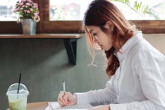 Jeune note asiatique attrayante d'écriture de femme d'affaires sur le bureau dans le bureau image libre de droits Jeune note asiatique attrayante d'écriture de femme d'affaires sur le bureau dans le bureau image libre de droits