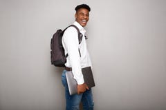 Jeune ordinateur portable heureux de participation d'étudiant masculin d'afro-américain par le mur gris image libre de droits Jeune ordinateur portable heureux de participation d'étudiant masculin d'afro-américain par le mur gris image libre de droits
