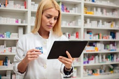 Jeune pharmacien f?minin s?rieux ? l'aide d'un comprim? dans une pharmacie image stock Jeune pharmacien f?minin s?rieux ? l'aide d'un comprim? dans une pharmacie image stock