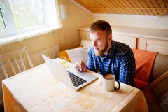 Jeune professionnel décontracté surfant l'Internet sur son ordinateur portable dans une salle à manger photos stock Jeune professionnel décontracté surfant l'Internet sur son ordinateur portable dans une salle à manger photos stock