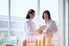 Jeune scientifique féminin se tenant avec le techer dans la fabrication de technicien de laboratoire photos stock Jeune scientifique féminin se tenant avec le techer dans la fabrication de technicien de laboratoire photos stock