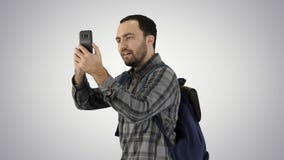 Jeune touriste attirant avec le sac à dos marchant et à l'aide du téléphone portable sur le fond de gradient images libres de droits Jeune touriste attirant avec le sac à dos marchant et à l'aide du téléphone portable sur le fond de gradient images libres de droits