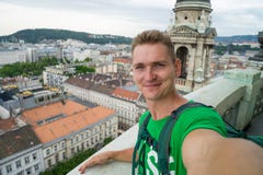 Jeune type attirant avec des yeux bleus prenant le selfie sur le point de vue supérieure avec Budapest sur le fond photos stock Jeune type attirant avec des yeux bleus prenant le selfie sur le point de vue supérieure avec Budapest sur le fond photos stock