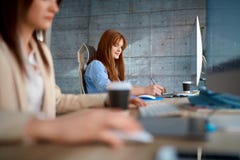 Jeune équipe travaillant au bureau - travailler femelle de concepteurs image stock Jeune équipe travaillant au bureau - travailler femelle de concepteurs image stock